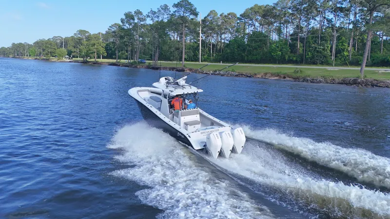 Engine Warranty X Trailer Yacht Photos Pics 2022 Yellowfin 34 boat cruising on a scenic river with lush green trees.