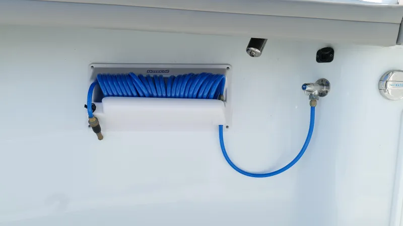 Engine Warranty X Trailer Yacht Photos Pics Blue coiled hose on 2022 Yellowfin 34 boat, mounted on white surface.