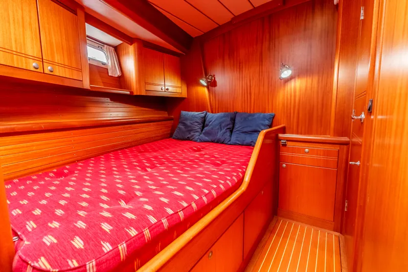 Luka Yacht Photos Pics Cozy cabin interior of 1997 Farr 60 Pilot House with wooden finish and red bedding.