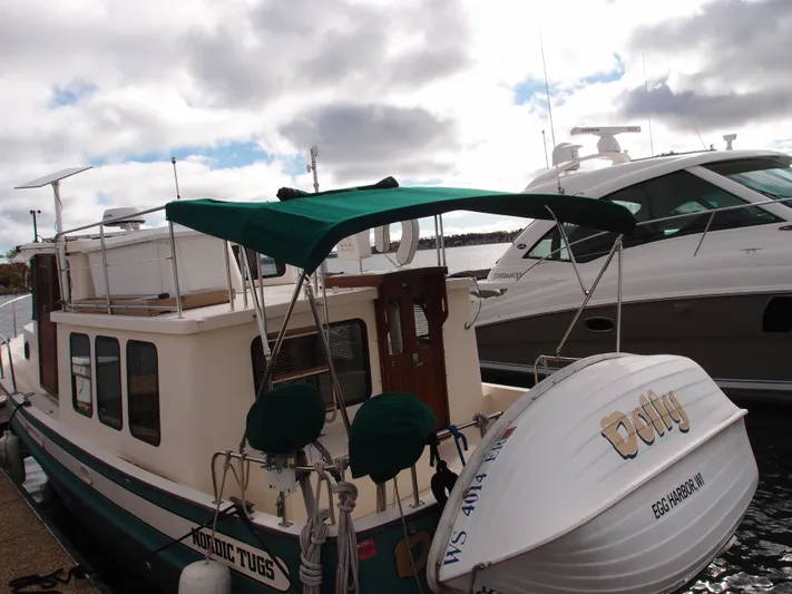 Dolly Yacht Photos Pics 1998 Nordic Tug 32 docked, featuring green canopy and adjacent luxury yacht.