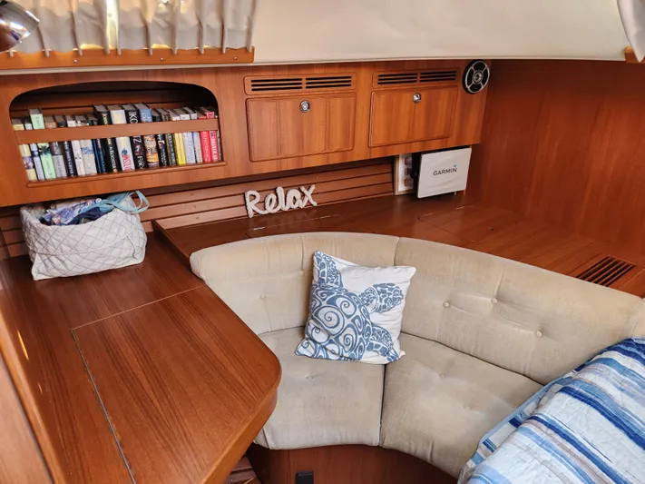 Bonnefooi Yacht Photos Pics Cozy interior of 2008 Hallberg-Rassy 62 yacht with books, cushions, and wooden finish.