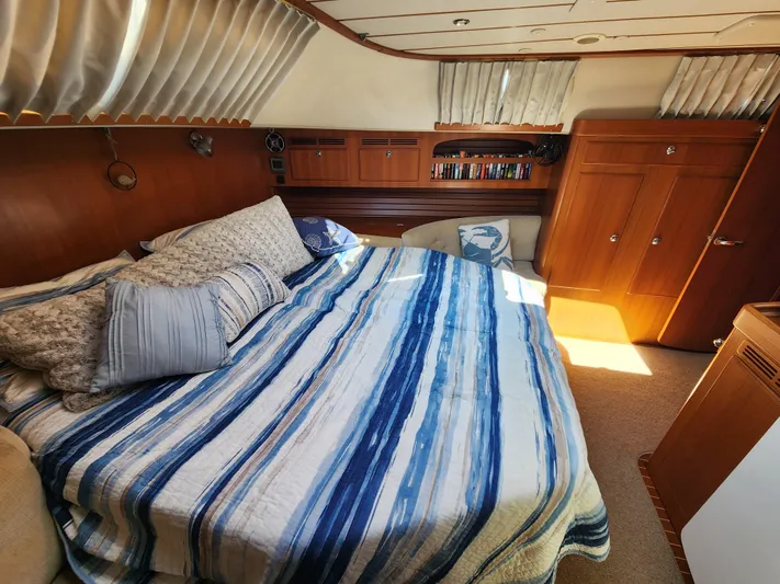 Bonnefooi Yacht Photos Pics Luxurious cabin interior of 2008 Hallberg-Rassy 62 yacht with striped bedding and wooden furnishings.