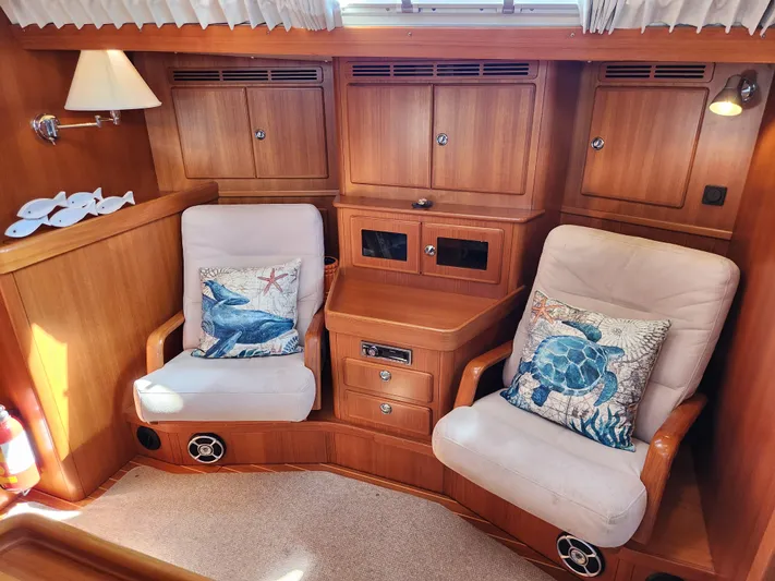 Bonnefooi Yacht Photos Pics Cozy interior of 2008 Hallberg-Rassy 62 yacht with plush seating and marine-themed cushions.