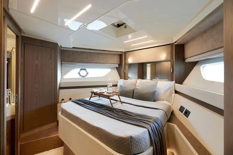  Yacht Photos Pics Luxurious bedroom interior of 2022 Ferretti Yachts 550 with elegant wood finishes and modern design.