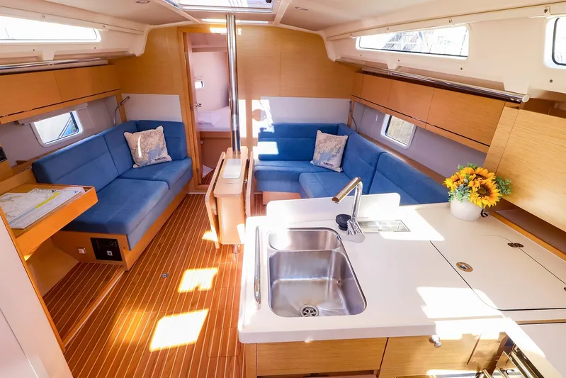  Yacht Photos Pics Modern 2022 Hanse 388 yacht interior with blue seating, wooden accents, and a bright kitchen area.