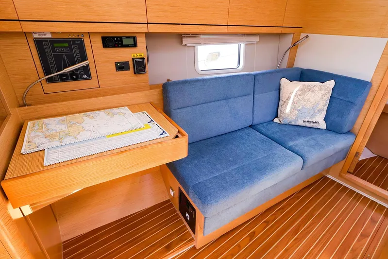  Yacht Photos Pics Interior of 2022 Hanse 388 yacht with blue sofa, navigation table, and nautical decor.