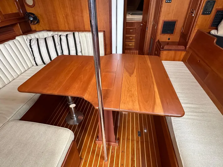 Elusive Yacht Photos Pics Interior of 1987 Hinckley Sou'wester 42 sailboat with wooden table and cushioned seating.