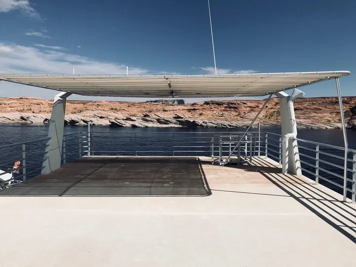 Cruisin (1/5 Share) Yacht Photos Pics Houseboat deck with sunshade, calm water, and rocky shoreline in the background.