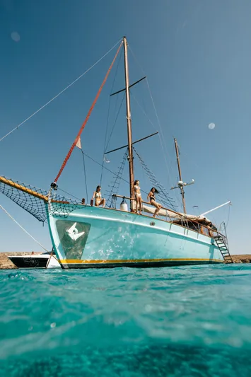 Kaiki Yacht Photos Pics Traditional Greek sailing yacht from 1974 on clear blue water, under a sunny sky.