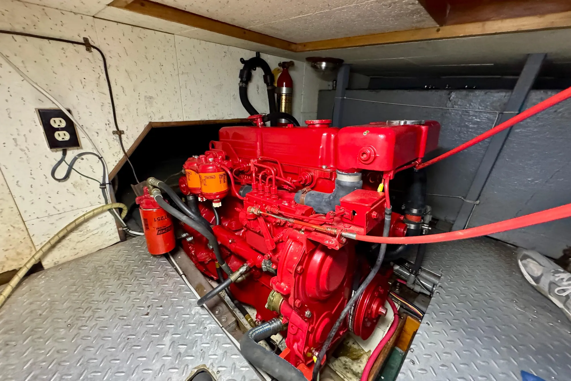 Red engine in 1982 Tung Hwa Seahorse boat, surrounded by metal flooring and wiring.