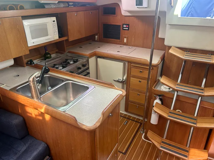 Dream Weaver Yacht Photos Pics Interior of 2003 Catalina 350 sailboat kitchen with wooden cabinetry and modern appliances.