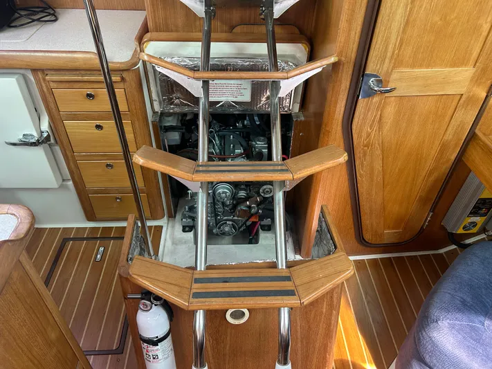 Dream Weaver Yacht Photos Pics Engine compartment of a 2003 Catalina 350 sailboat with wooden interior and steps.