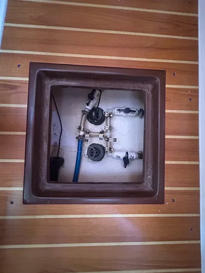 Dream Weaver Yacht Photos Pics Boat plumbing system in a 2003 Catalina 350, featuring valves and pipes on a wooden deck.