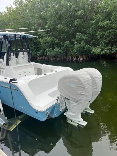  Yacht Photos Pics 2023 Sportsman Open 302 Center Console boat docked near lush greenery.