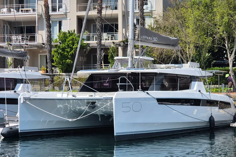 Tafika Yacht Photos Pics 2024 Leopard 50 catamaran docked in a marina, surrounded by modern buildings.