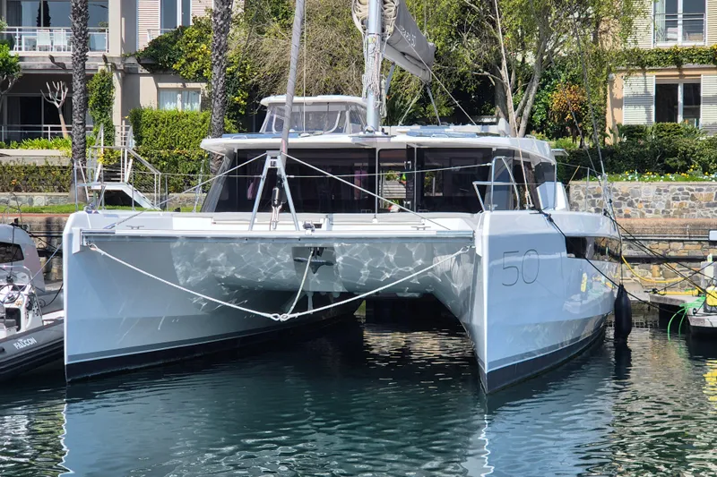 Tafika Yacht Photos Pics 2024 Leopard 50 catamaran docked in a marina, surrounded by greenery and buildings.