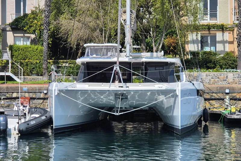 Tafika Yacht Photos Pics 2024 Leopard 50 catamaran docked in a marina, surrounded by lush greenery.