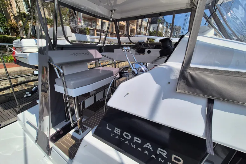 Tafika Yacht Photos Pics 2024 Leopard 50 catamaran cockpit with modern seating and controls, docked in a marina.