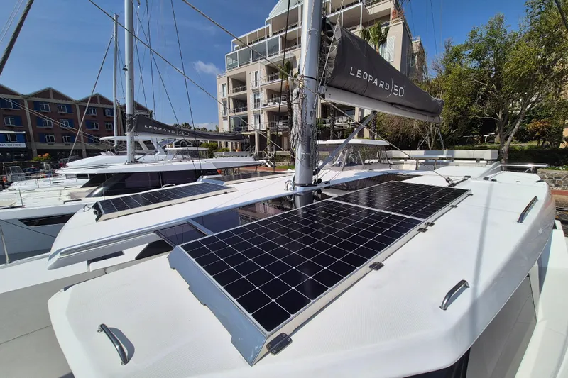Tafika Yacht Photos Pics 2024 Leopard 50 yacht with solar panels docked near modern buildings.