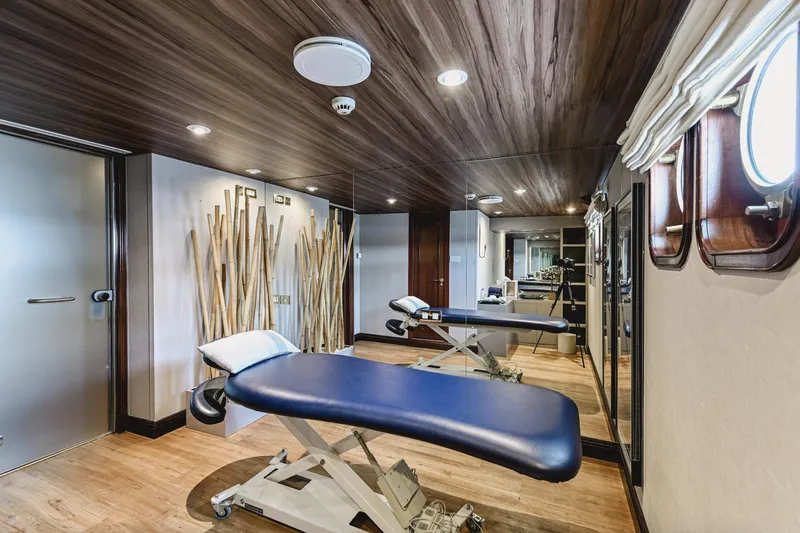 Chakra Yacht Photos Pics Luxurious yacht interior with massage table, wooden accents, and porthole windows, Devonport 86m, 1963.