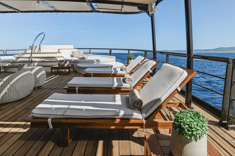 Chakra Yacht Photos Pics Luxurious yacht deck with sun loungers, ocean view, and elegant seating on Devonport 86m, 1963 model.