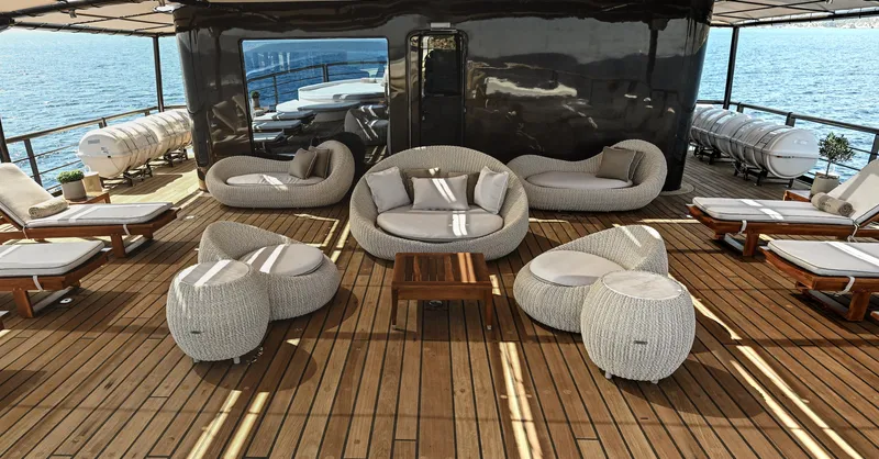 Chakra Yacht Photos Pics Luxurious yacht deck with modern seating, wooden flooring, and ocean view. Devonport 86m, 1963 model.