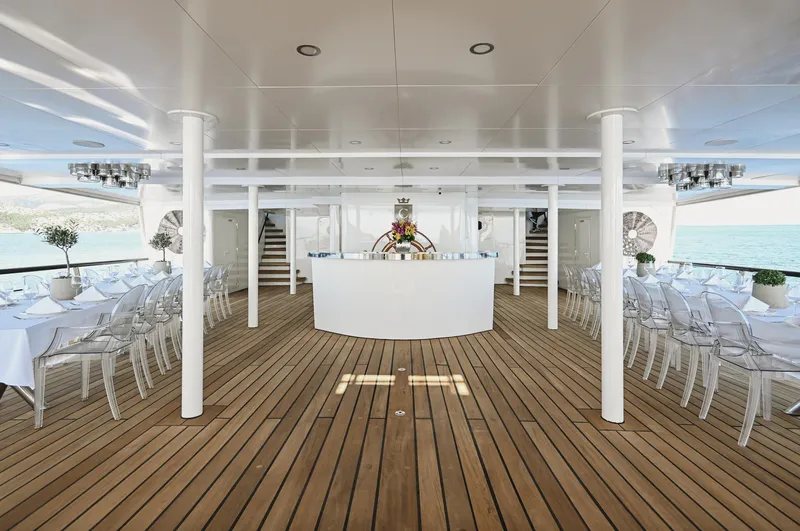 Chakra Yacht Photos Pics Luxurious yacht deck with elegant dining setup, featuring wooden flooring and ocean views. Devonport 86m, 1963.