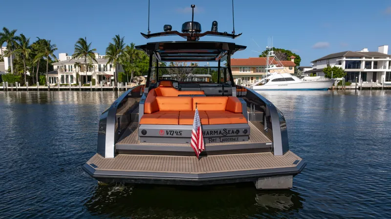 Pharmasea Yacht Photos Pics 2022 Vanquish Yachts VQ45 with orange seating, docked in a scenic waterfront area.