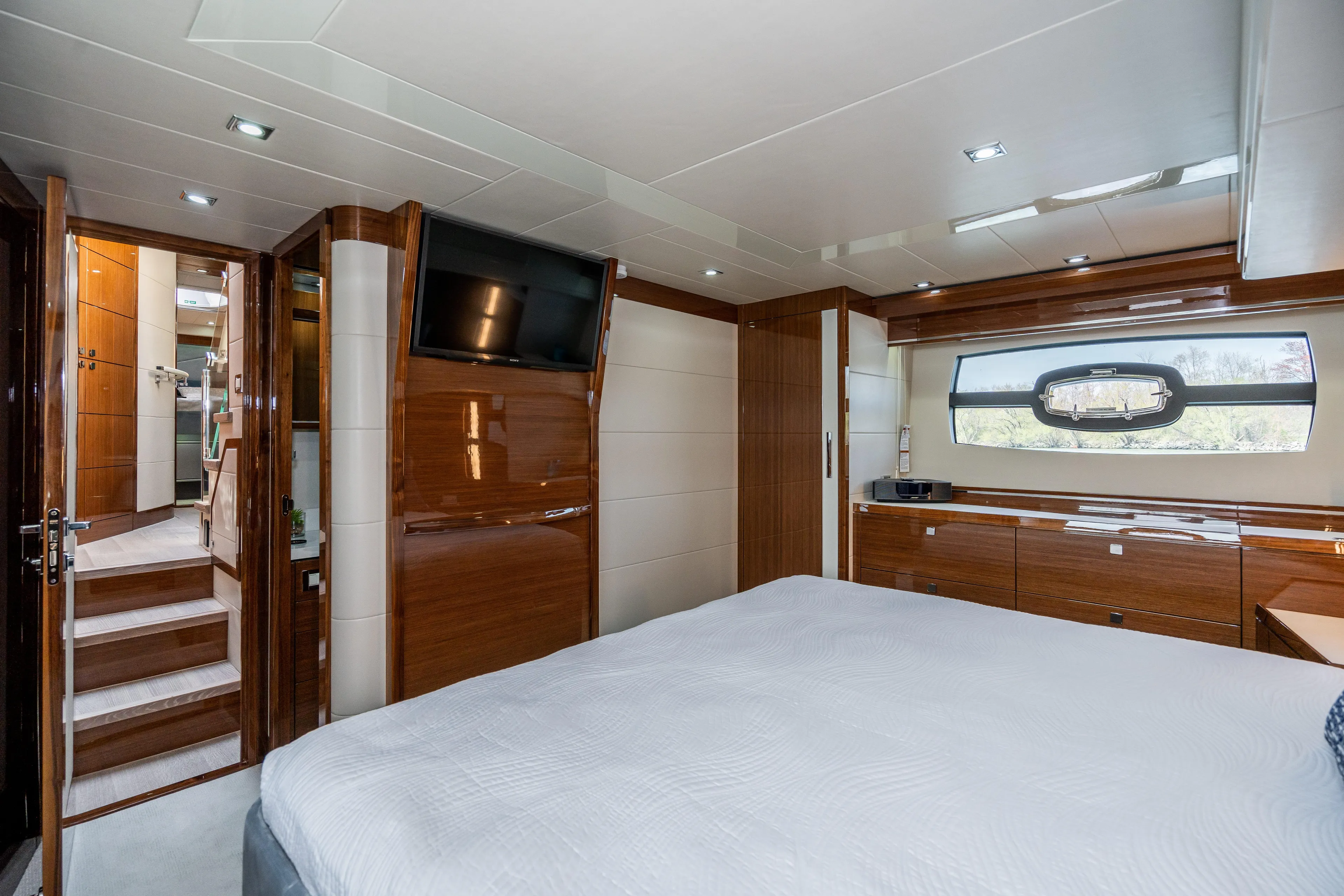  Yacht Photos Pics Luxurious Neptunus 650F 2026 yacht bedroom with modern wood finishes and large window.