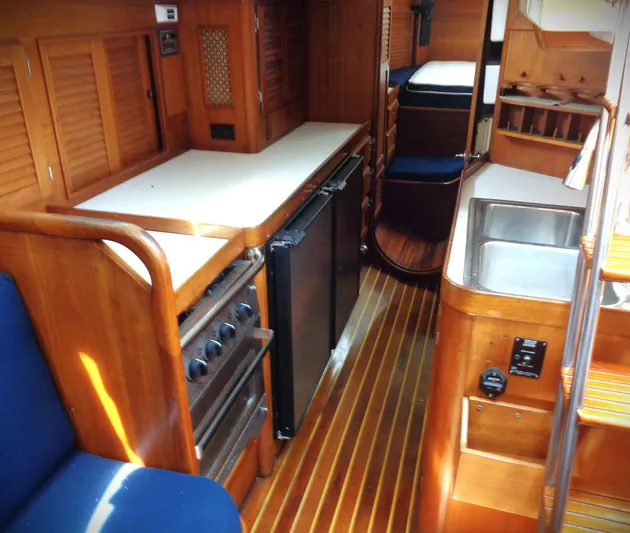  Yacht Photos Pics 1983 Bristol 41.1 yacht interior with wooden cabinetry, compact kitchen, and cozy seating area.