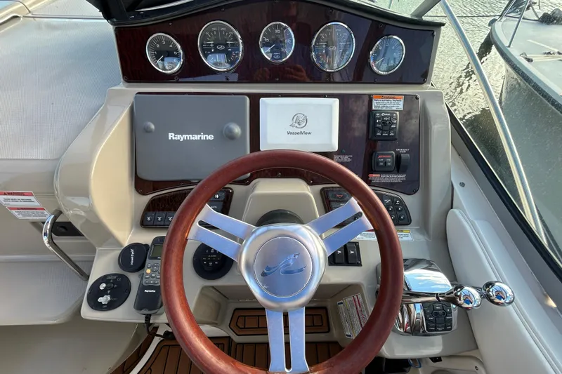  Yacht Photos Pics Cockpit of 2010 Sea Ray Sundancer 330 with Raymarine navigation system and wood-accented steering wheel.