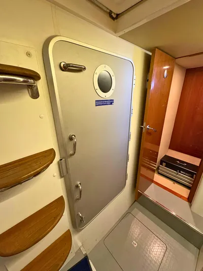  Yacht Photos Pics Interior of 2007 Princess 21M yacht showing a metal door with porthole and wooden steps.