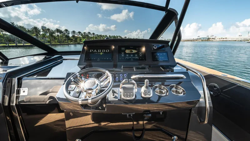 Love$ick Yacht Photos Pics 2023 Pardo Yachts P50 helm with modern controls and scenic waterfront view.