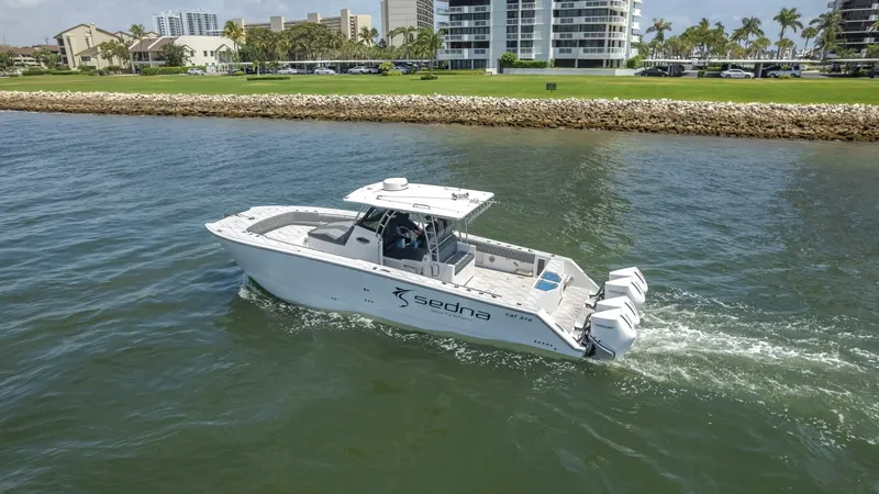  Yacht Photos Pics 2025 Sedna 37 Open boat cruising on water near a coastal cityscape.