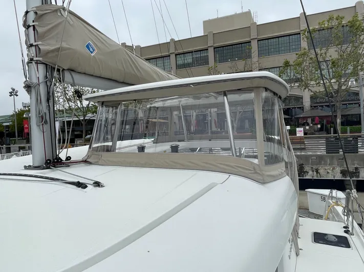 Hullchal Yacht Photos Pics 2021 Lagoon 42 sailboat with covered cockpit, docked near modern building.