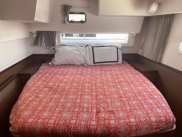 Hullchal Yacht Photos Pics Interior cabin of 2021 Lagoon 42 with a cozy bed and red patterned bedding.