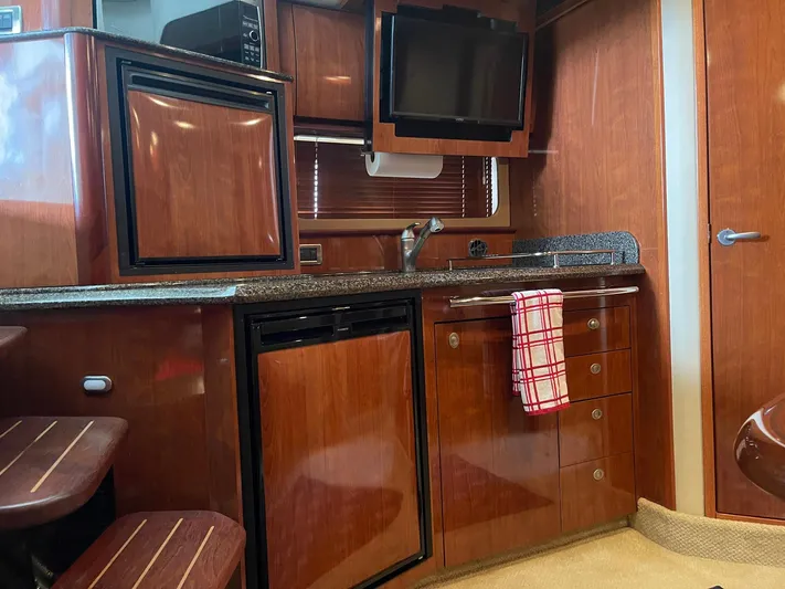 Knot Justified Yacht Photos Pics 2006 Sea Ray 38 Sundancer galley with wood cabinetry, countertop, and appliances.