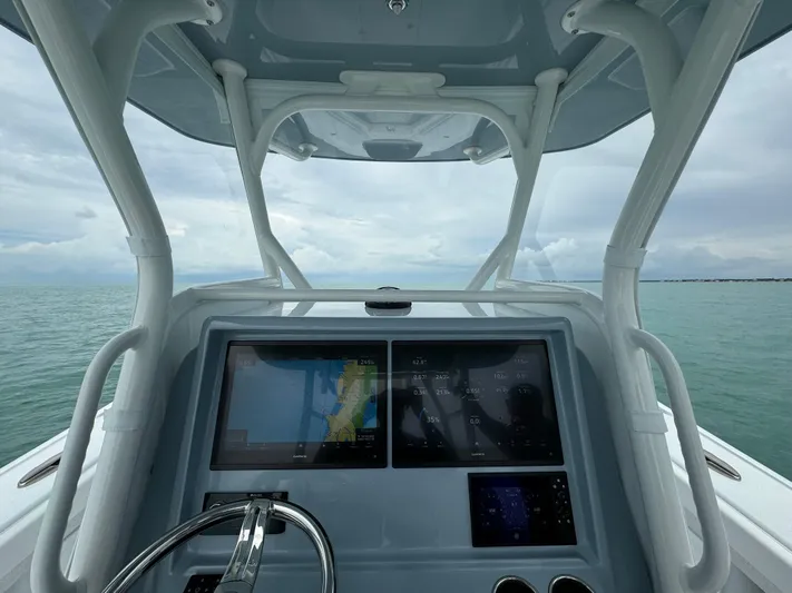  Yacht Photos Pics Yellowfin 32 boat dashboard with navigation screens, steering wheel, and ocean view, 2025 model.