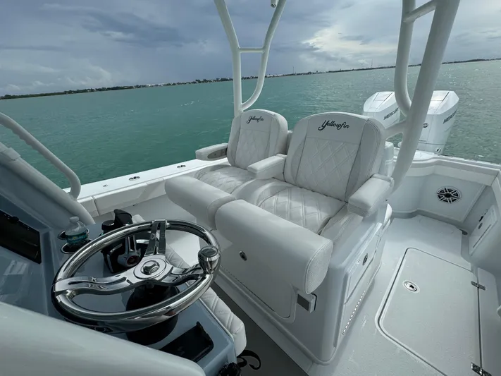  Yacht Photos Pics 2025 Yellowfin 32 boat interior with white seating and steering wheel, overlooking calm waters.