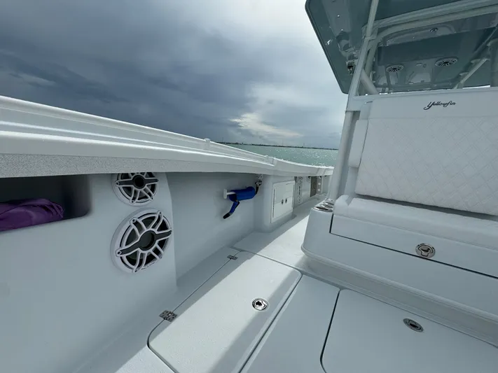  Yacht Photos Pics 2025 Yellowfin 32 boat interior with speakers and seating under cloudy sky.