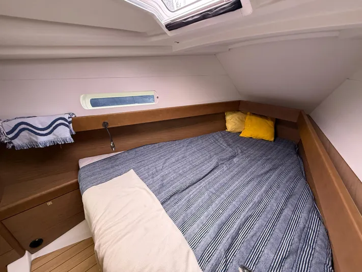 Windwaker Yacht Photos Pics Cozy cabin interior of 2013 Jeanneau 41 DS sailboat with striped bedding and wooden accents.