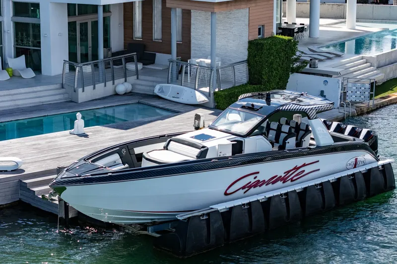  Yacht Photos Pics 2024 Cigarette 42 Auroris luxury boat docked by modern waterfront home.