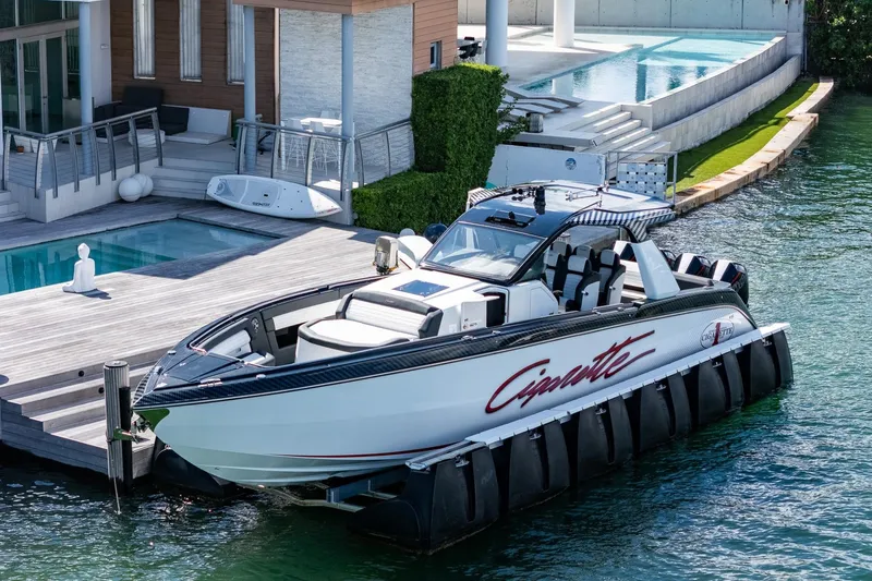  Yacht Photos Pics 2024 Cigarette 42 Auroris luxury boat docked by modern waterfront home.