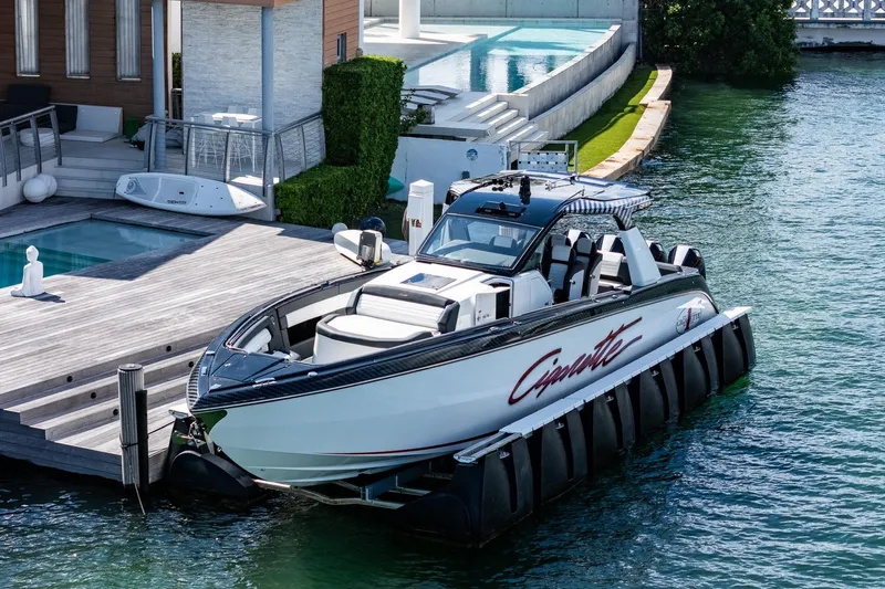  Yacht Photos Pics 2024 Cigarette 42 Auroris luxury boat docked by modern waterfront home.