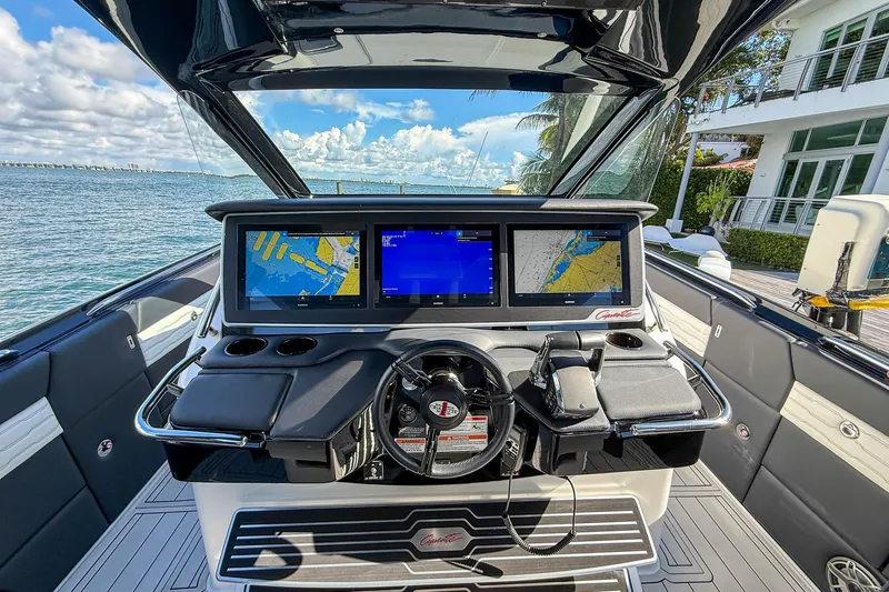  Yacht Photos Pics 2024 Cigarette 42 Auroris boat dashboard with navigation screens, steering wheel, and waterfront view.