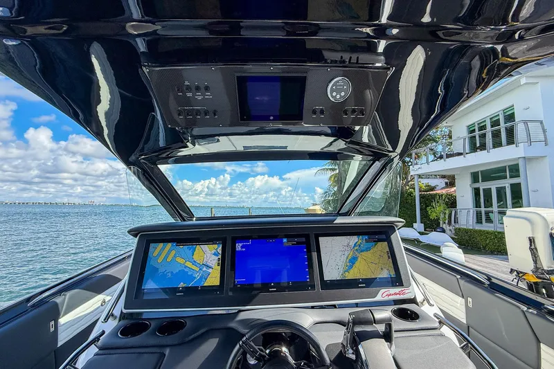  Yacht Photos Pics 2024 Cigarette 42 Auroris boat cockpit with advanced navigation screens, docked by waterfront home.