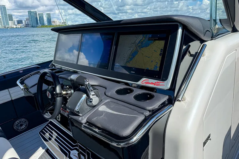  Yacht Photos Pics 2024 Cigarette 42 Auroris boat dashboard with navigation screens, steering wheel, and city skyline view.