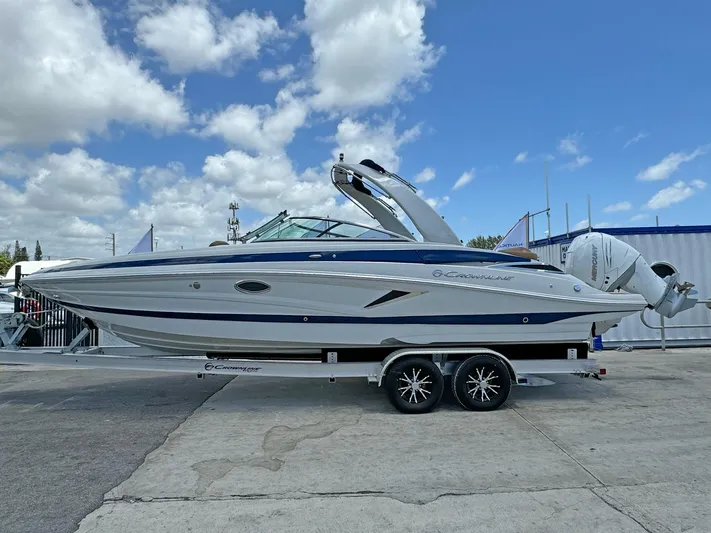 Yacht Photos Pics 2024 Crownline 290 XSS boat on trailer under blue sky with clouds.