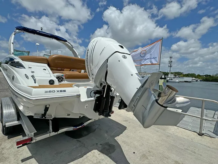  Yacht Photos Pics 2024 Crownline 290 XSS boat with powerful outboard motor, docked under a bright blue sky.