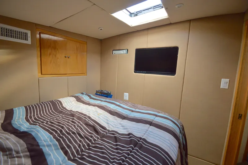 Hopium Yacht Photos Pics Cozy bedroom interior of 2004 Chesapeake 58 boat with striped bedding and wall-mounted TV.